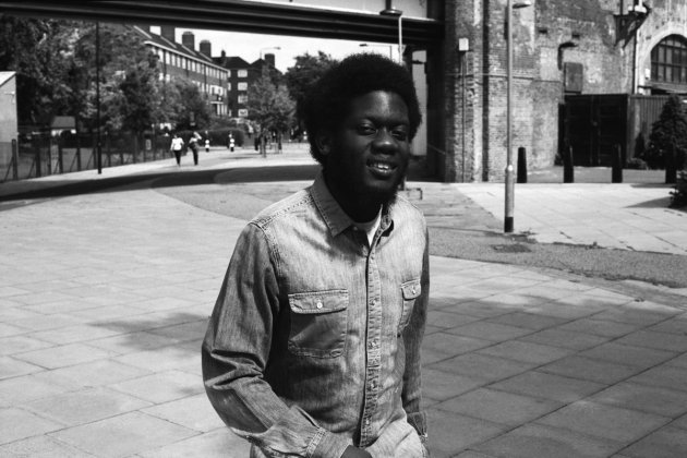 Michael Kiwanuka, Straße, Fußgänger, Pedestrian Precinct,Brücke, Menschen, schwarz weiß, Bart, Afro, Jeanshemd, Laterne, Mauer, Häuser, Bäume, Fenster, Backstein